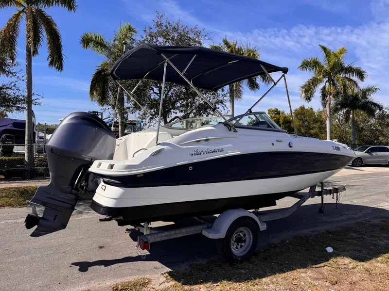 Slide: The Image of 2017 Hurricane 2000SD boat on trailer, parked near palm trees under blue sky. - 4