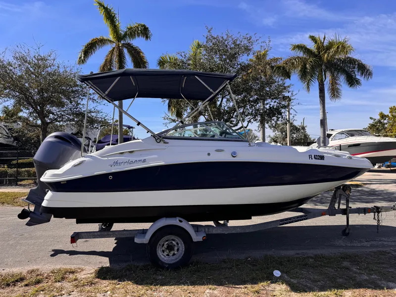 Slide: The Image of 2017 Hurricane 2000SD boat on trailer, parked outdoors with palm trees in background. - 5