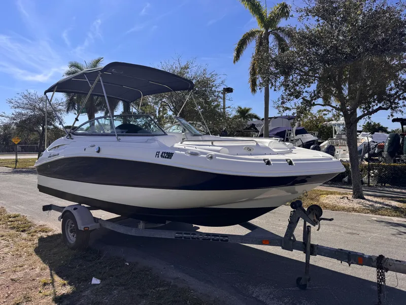 Slide: The Image of 2017 Hurricane 2000SD boat on trailer, parked under palm trees, clear blue sky. - 7