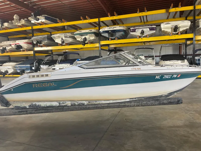 The Image of 1993 Regal 176 SE boat in storage, surrounded by other boats on racks. - 1