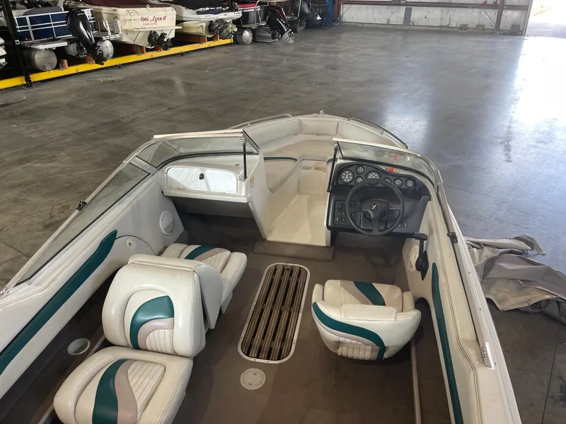 Slide: The Image of 1993 Regal 176 SE boat interior with white and teal seating in a storage facility. - 9