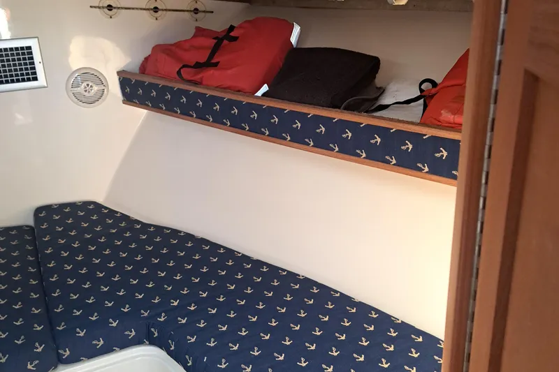 Slide: The Image of 2003 Carolina Classic 28 Express Sportfisherman cabin with anchor-patterned bedding and storage shelf. - 10