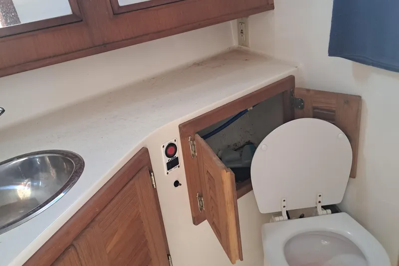 Slide: The Image of 2003 Carolina Classic 28 Express Sportfisherman boat bathroom with sink and open cabinet. - 12