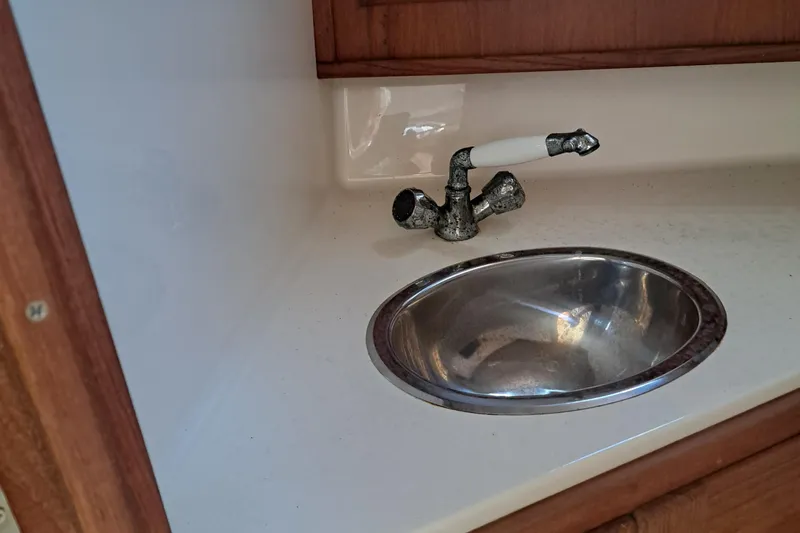 Slide: The Image of 2003 Carolina Classic 28 Express Sportfisherman sink with vintage faucet in wooden cabinet. - 13