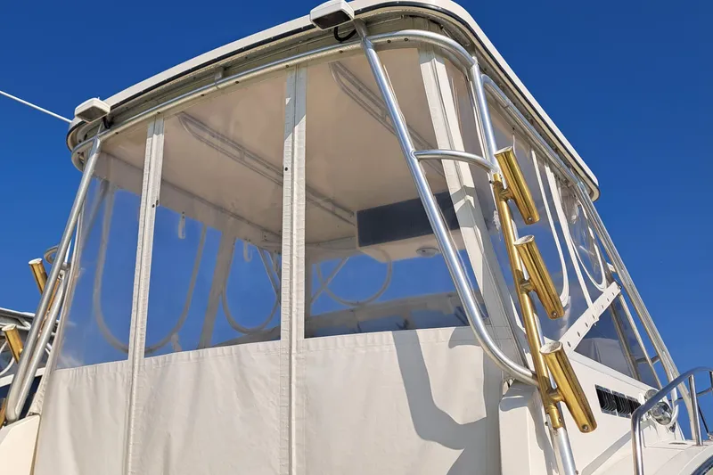 Slide: The Image of 2003 Carolina Classic 28 Express Sportfisherman with clear enclosure and rod holders against blue sky. - 7