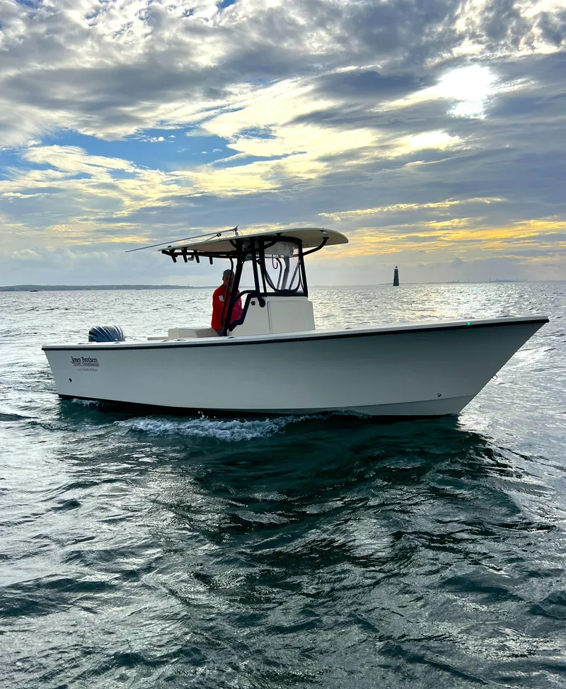 Slide: The Image of 2024 Jones Brothers Cape Fisherman 26 Light Tackle boat cruising on open water at sunset. - 12
