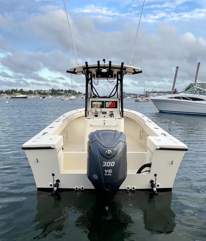 Slide: The Image of 2024 Jones Brothers Cape Fisherman 26 Light Tackle boat on water, rear view with outboard motor. - 4