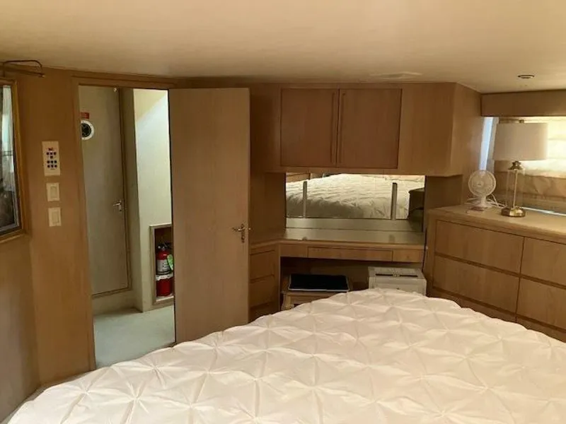 Slide: The Image of Bedroom interior of 1996 Hatteras 70 Sport Deck Motor Yacht, featuring wood cabinetry and cozy decor. - 26