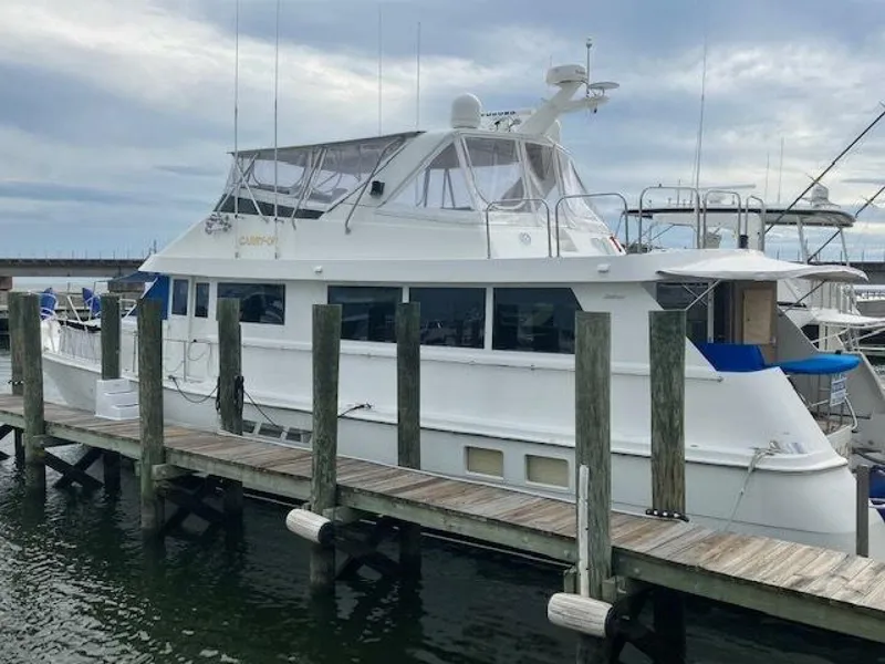 Slide: The Image of 1996 Hatteras 70 Sport Deck Motor Yacht docked at marina under cloudy sky. - 2