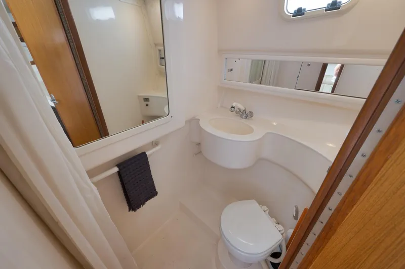 Slide: The Image of 2006 Cabo 32 Express boat bathroom with sink, toilet, mirror, and towel. - 33