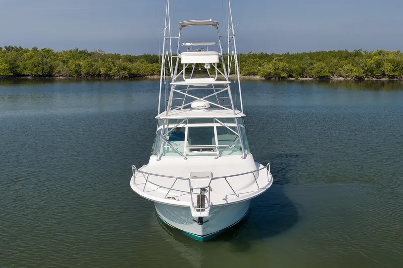 Slide: The Image of 2006 Cabo 32 Express boat on calm water, surrounded by lush greenery. - 12