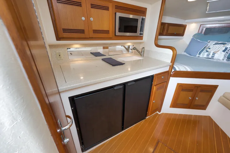 Slide: The Image of 2006 Cabo 32 Express yacht interior with kitchenette, microwave, and cozy sleeping area. - 30