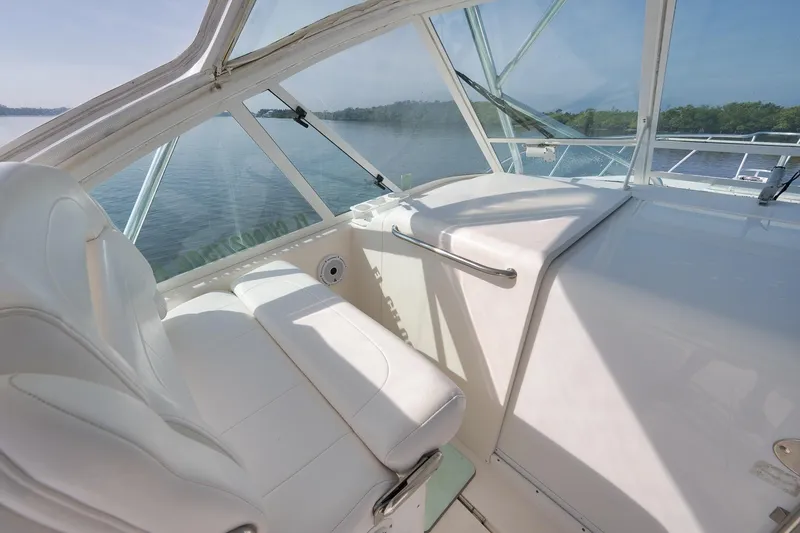 Slide: The Image of 2006 Cabo 32 Express boat interior with white seating and clear windows overlooking water. - 20