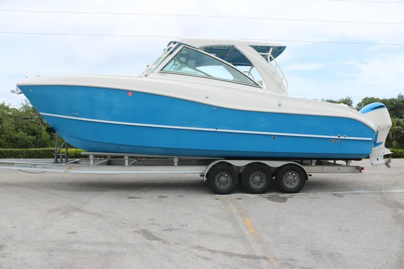 Slide: The Image of 2017 World Cat 320DC boat on trailer, blue and white design, parked outdoors. - 1