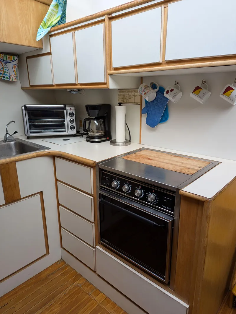 Slide: The Image of Compact kitchen with modern appliances, wooden cabinets, and a 1988 Custom Hi-tech 44 stove. - 17