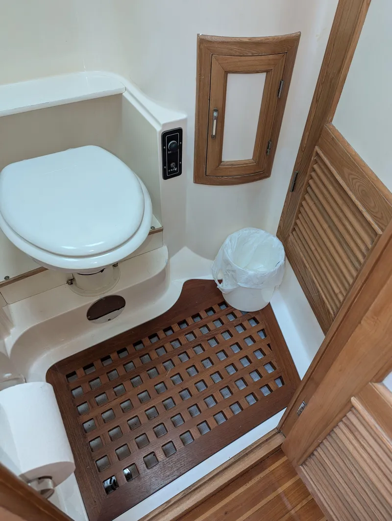 Slide: The Image of Compact boat bathroom with wooden accents, featuring a toilet and a small trash bin. - 19