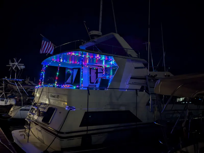Slide: The Image of Custom Hi-tech 44 boat with colorful lights and American flag at night, 1988 model. - 2