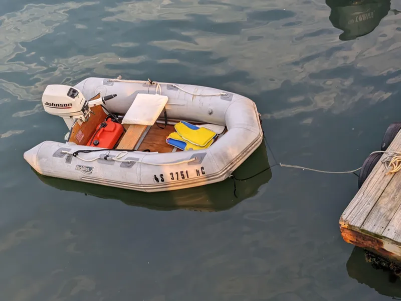Slide: The Image of Inflatable boat with Johnson motor, docked on calm water, Custom Hi-tech 44, 1988 model. - 3