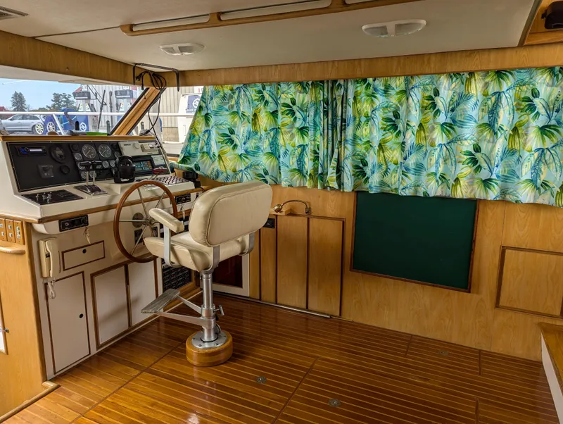 Slide: The Image of 1988 Custom Hi-tech 44 boat interior with wooden steering wheel and tropical curtains. - 9