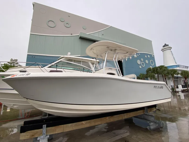 The Image of 2018 Release 208 SXC boat displayed outdoors near a modern building and lighthouse. - 1