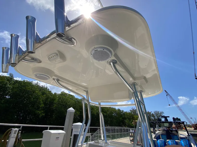 Slide: The Image of 2018 Release 208 SXC boat canopy with rod holders and speakers under sunny sky. - 13