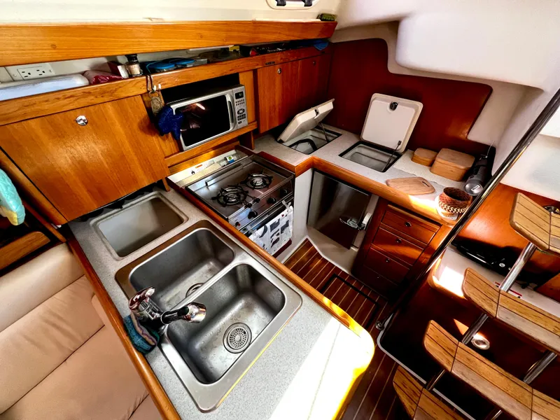 Slide: The Image of Cozy kitchen in a 2007 Catalina 350 sailboat with wood cabinetry and modern appliances. - 33