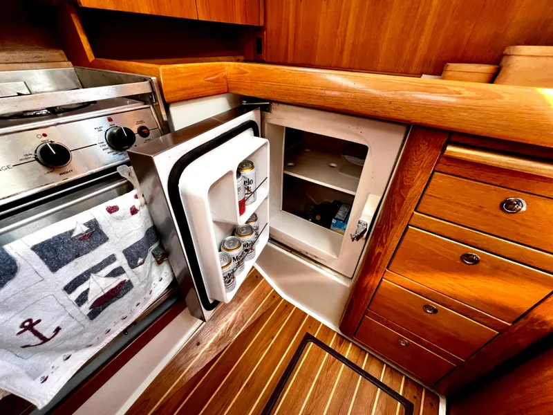 Slide: The Image of Galley of 2007 Catalina 350 yacht with fridge, stove, and wooden cabinetry. - 34