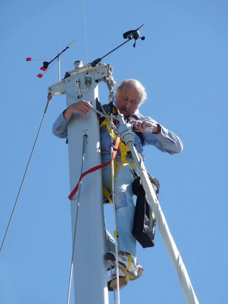 Slide: The Image of Man working on Catalina 350 sailboat mast, clear blue sky background. - 5