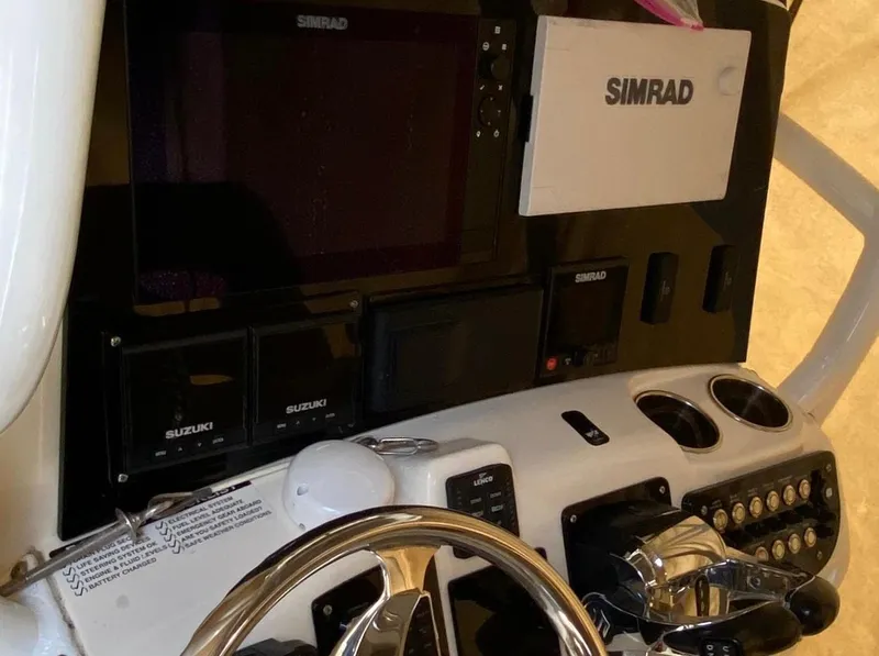 Slide: The Image of 2018 NauticStar 28 XS Offshore boat on calm water, surrounded by trees and docks. - 3