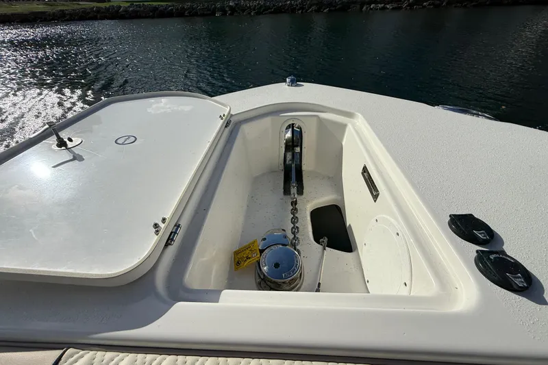 Slide: The Image of 2018 NauticStar 28 XS boat anchor compartment with chain and winch, docked on calm water. - 39