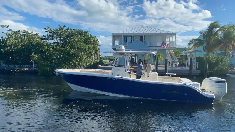 Slide: The Image of 2018 NauticStar 28 XS Offshore boat cruising near waterfront homes. - 44