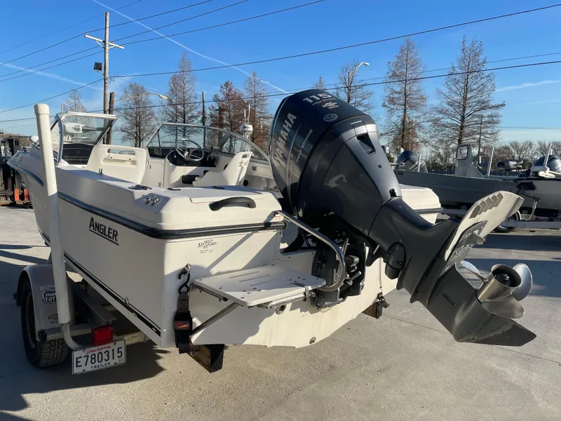 Slide: The Image of 2002 Angler 18 DC boat on trailer with American flag, parked outside a modern building. - 3