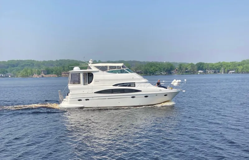 The Image of 2004 Carver 466 Motor Yacht cruising on a serene lake under a clear blue sky. - 0