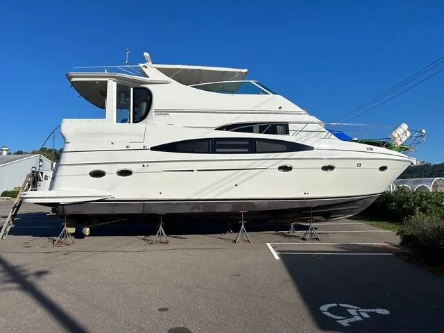Slide: The Image of 2004 Carver 466 Motor Yacht cruising on a serene lake under a clear blue sky. - 1