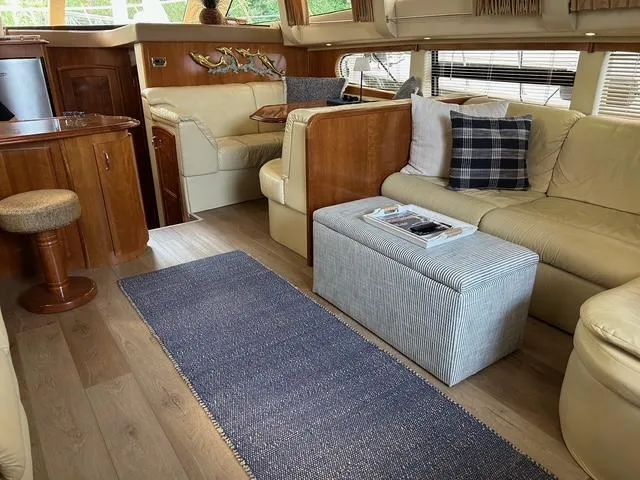 Slide: The Image of 2004 Carver 466 Motor Yacht interior with a mounted flat-screen TV and white seating. - 11