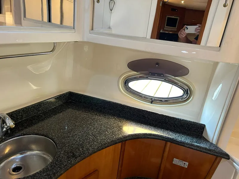 Slide: The Image of 2004 Carver 466 Motor Yacht interior with wooden cabinetry and cozy bedroom setup. - 22