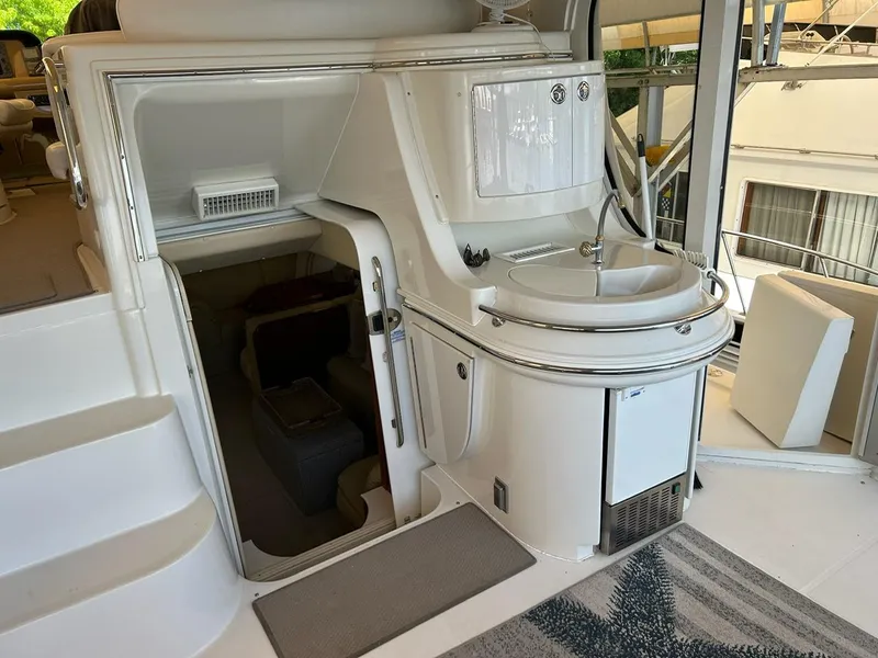 Slide: The Image of 2004 Carver 466 Motor Yacht deck with chairs, table, and ottomans overlooking water. - 6