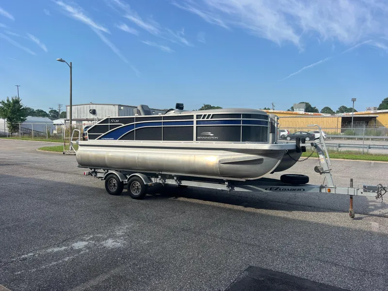 Slide: The Image of 2022 Bennington SX 20 Swingback pontoon boat on trailer, parked outdoors. - 1