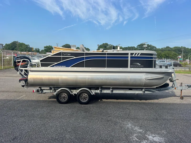 Slide: The Image of 2022 Bennington SX 20 Swingback pontoon boat on trailer, parked outdoors. - 2