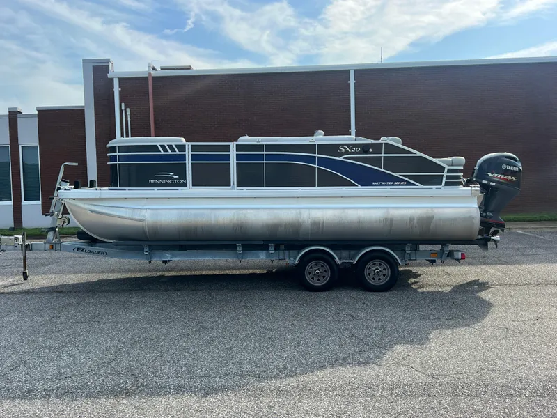 Slide: The Image of 2022 Bennington SX 20 Swingback pontoon boat on trailer, parked outdoors. - 6