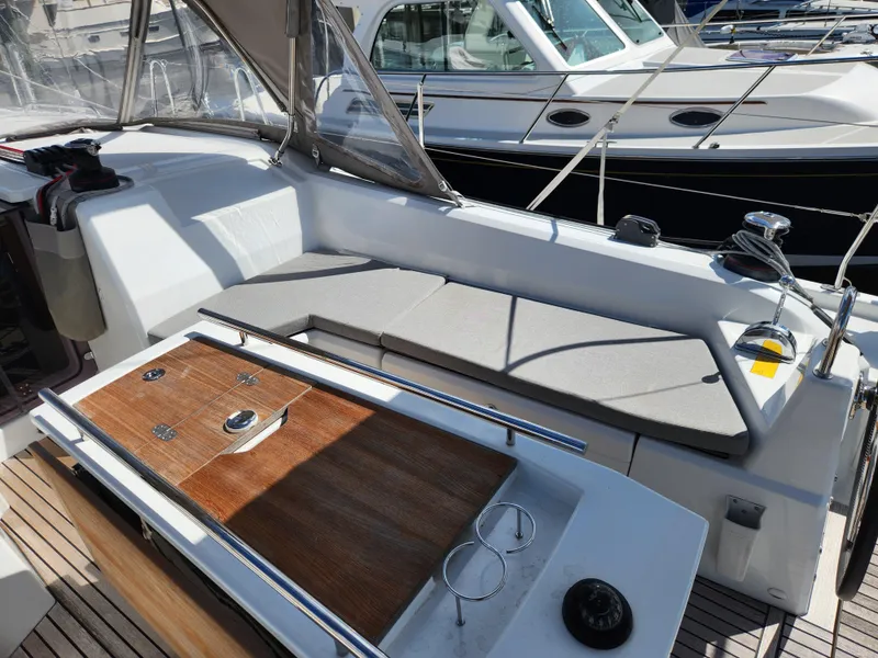 Slide: The Image of 2022 Beneteau Oceanis 40.1 yacht cockpit with cushioned seating and wooden table. - 27