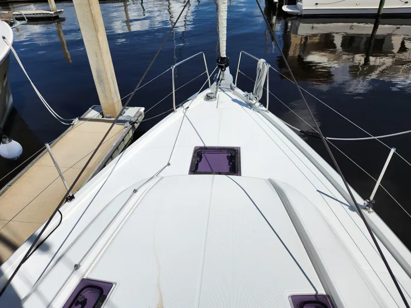 Slide: The Image of 2022 Beneteau Oceanis 40.1 sailboat docked, showcasing sleek deck design and marina reflections. - 38