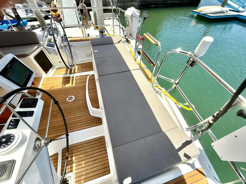 Slide: The Image of 2018 Jeanneau 58 yacht deck with steering wheel, navigation equipment, and cushioned seating. - 38