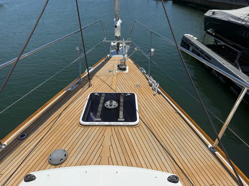 Slide: The Image of Deck view of 2018 Jeanneau 58 yacht, featuring sleek wooden finish and marina backdrop. - 41