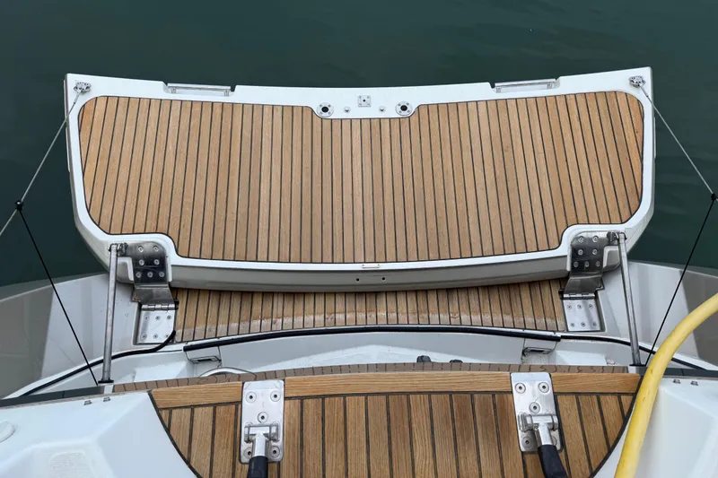 Slide: The Image of 2018 Jeanneau 58 yacht with teak swim platform and deck, docked on calm water. - 47
