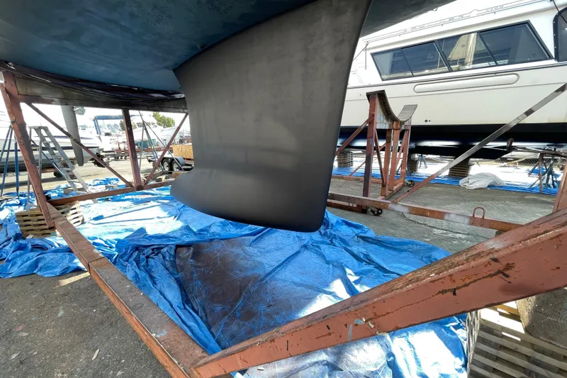 Slide: The Image of 2018 Jeanneau 58 sailboat keel on dry dock, supported by metal stands and blue tarps. - 53