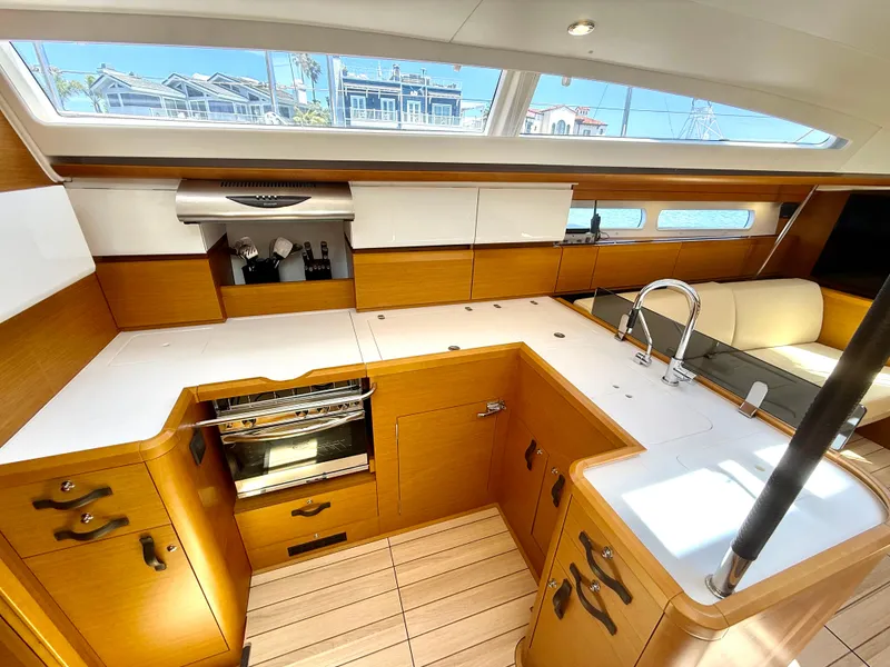 Slide: The Image of Luxurious 2018 Jeanneau 58 yacht kitchen with modern appliances and sleek wood finish. - 6