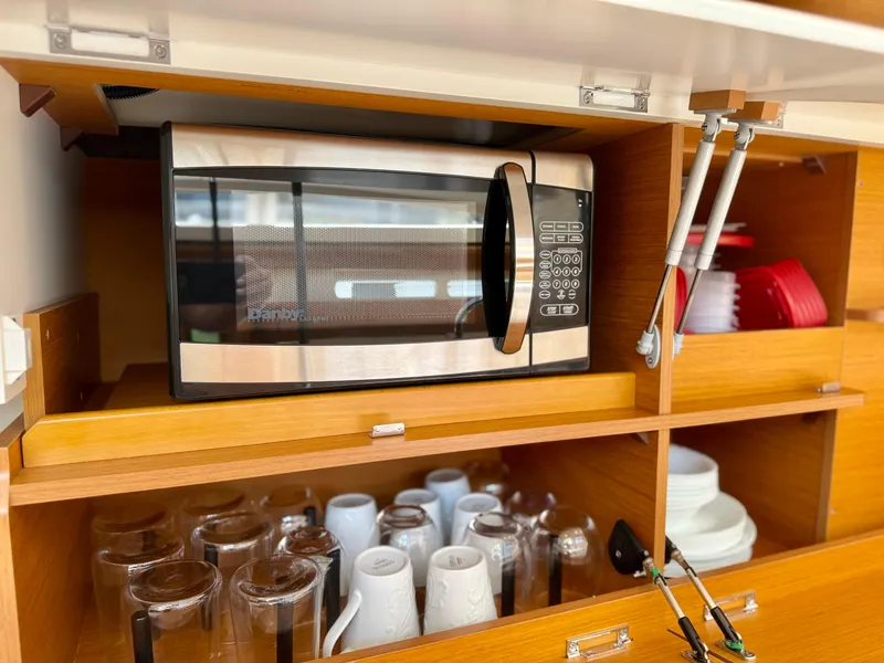 Slide: The Image of Modern kitchen setup on a 2018 Jeanneau 58 yacht with microwave and organized dishware. - 7