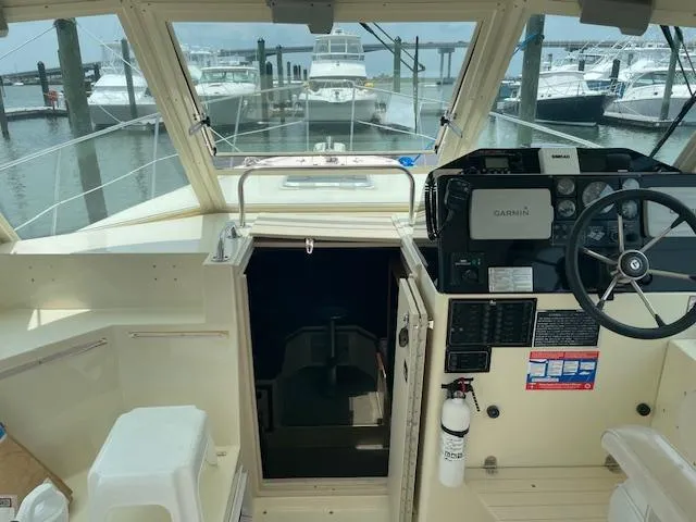 Slide: The Image of 2001 Albin 31' Tournament Express cockpit with steering wheel, Garmin system, and marina view. - 5