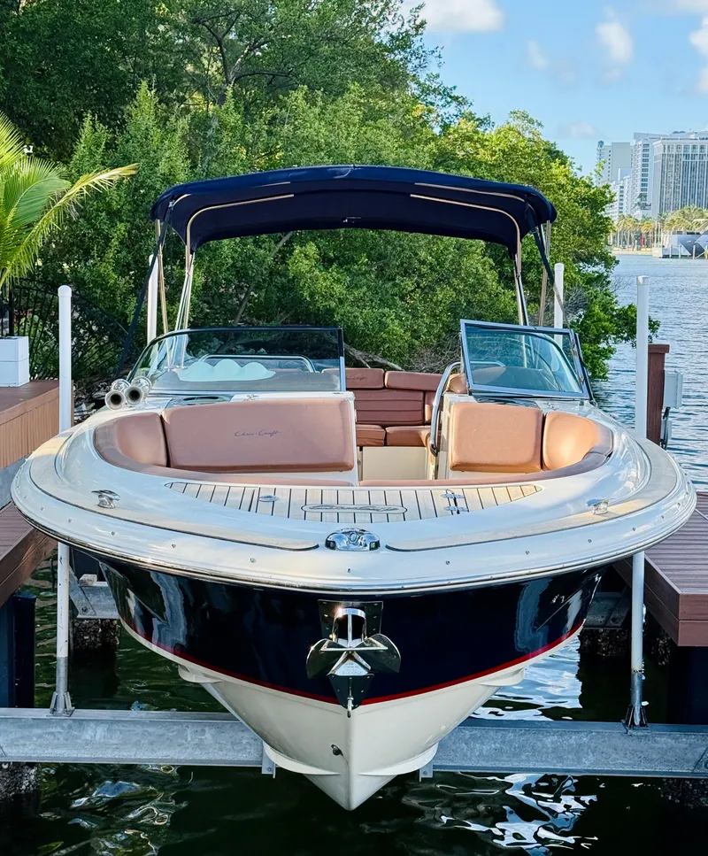 Slide: The Image of 2015 Chris-Craft Launch 32 boat docked by lush greenery. - 2